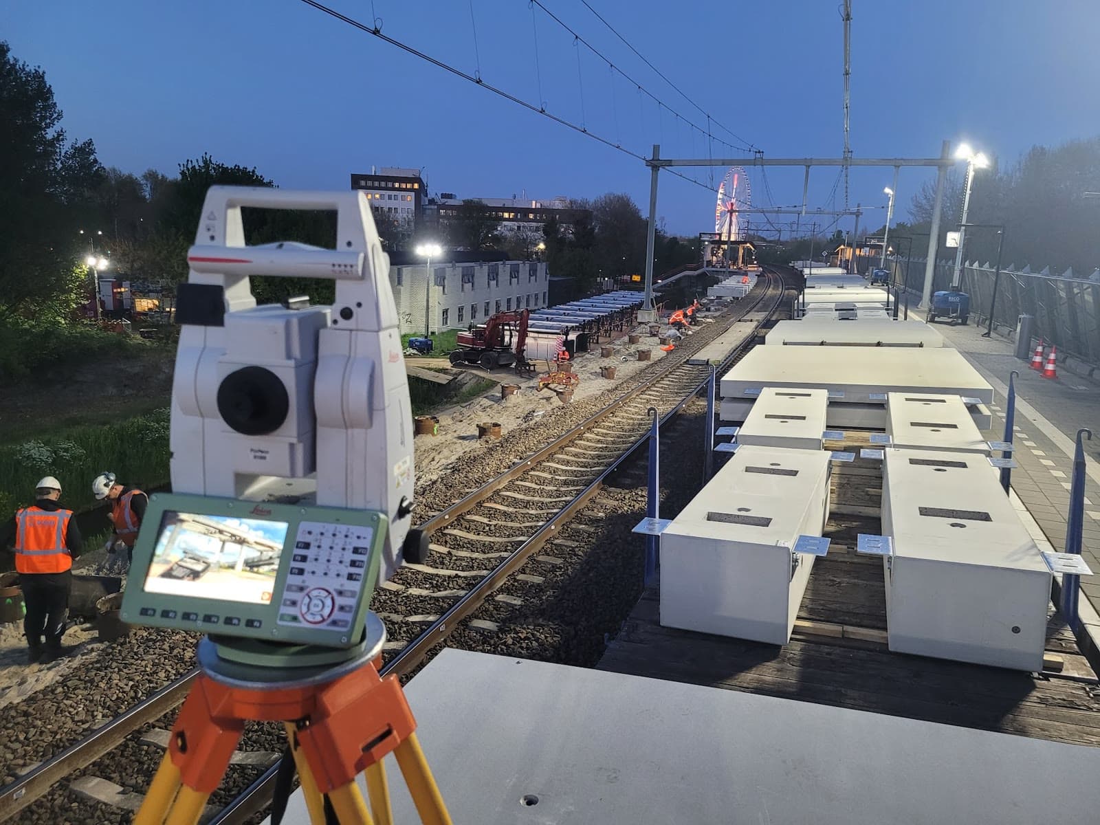 Total station meetwerk bij spoorwegproject in de avond